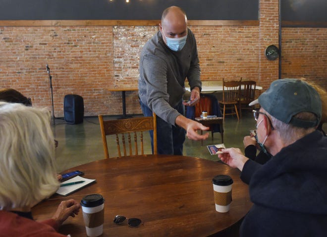 Democratic Iowa-4th congressional district candidate JD Scholten distributes his baseball card during the " Coffee with the Candidate" event at Farm Ground Coffee Saturday, Oct. 17, 2020, in Nevada, Iowa.